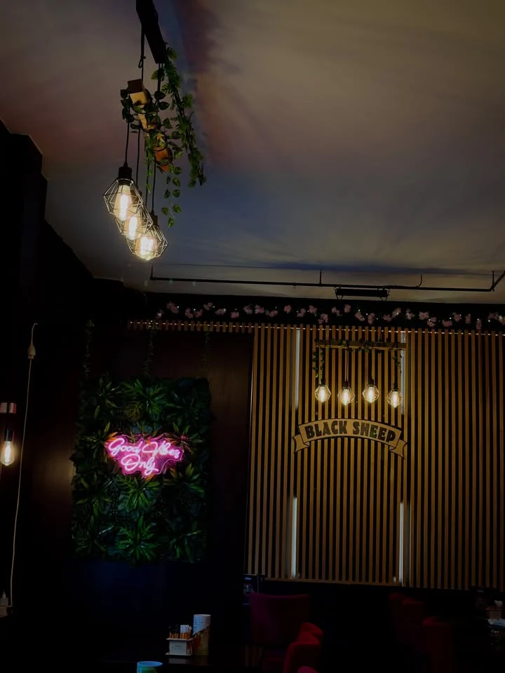 Innenraum des Black Sheep mit Neonlicht und Holzlamellenwand